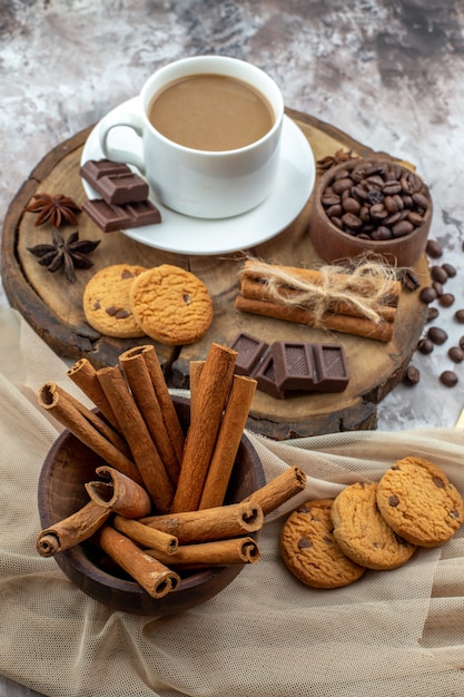 Onderaanzicht kopje koffie koekjes kom met koffiebonen chocolade kaneelstokjes in kom anijs sterren op houten bord op tafel