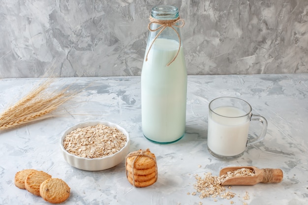 onderaanzicht melkglas en melkfles koekjes haver kom tarwe spikes op grijze achtergrond