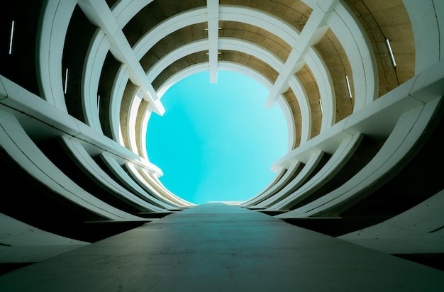 Onderaanzicht parkeergarage met meerdere verdiepingen met uitzicht op de blauwe lucht in het midden Architectuur van spiral