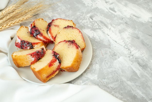 Onderaanzicht plakjes jamcake op bord tarwe spikes op tafel kopieerplaats