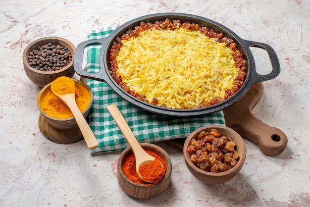 onderaanzicht smakelijke plov in grote pan kurkuma zwarte en rode pepers in kommen op tafel