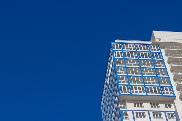 Onderaanzicht van de gevel van een hoog woongebouw tegen een blauwe lucht