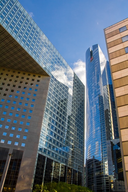 Onderaanzicht van de glazen wolkenkrabbers van het zakelijke district van La Defense van Parijs tegen een blauwe bewolkte hemel