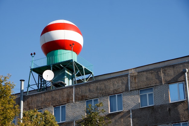 Onderaanzicht van de rood-witte bol op het gebouw van de meteorologische dienst tegen de blauwe hemel