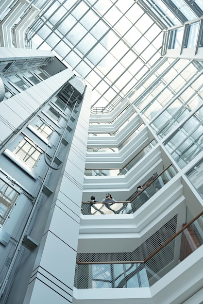 Onderaanzicht van verschillende zakenmensen die werkpunten bespreken terwijl ze op een van de balkons in een groot kantoorcentrum staan