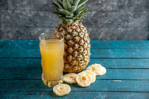 onderaanzicht verse ananassap glas gedroogde ananas ringen op blauwe houten achtergrond