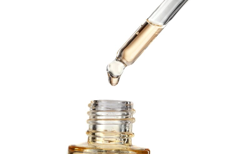 Foto onderdeel van een fles met geel cosmetisch serum cosmetische glazen pipet met een gele olieachtige druppel