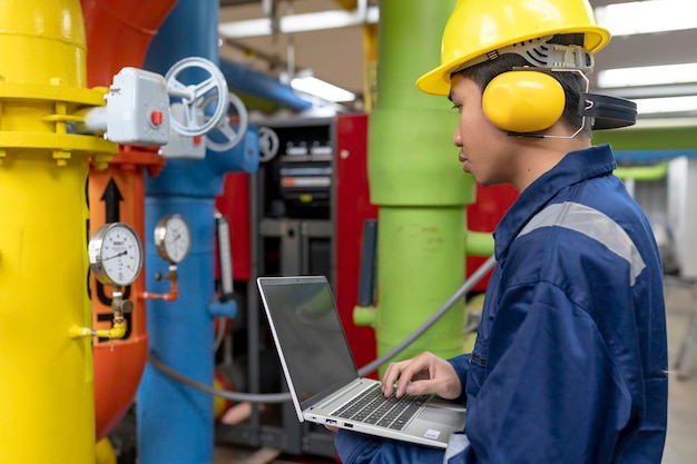 Onderhoudsmonteur bij een verwarmingsinstallatiePetrochemische arbeiders houden toezicht op de werking van gas- en oliepijpleidingen in de fabriek Ingenieurs plaatsen gehoorbeschermers Bij kamer met veel leidingen