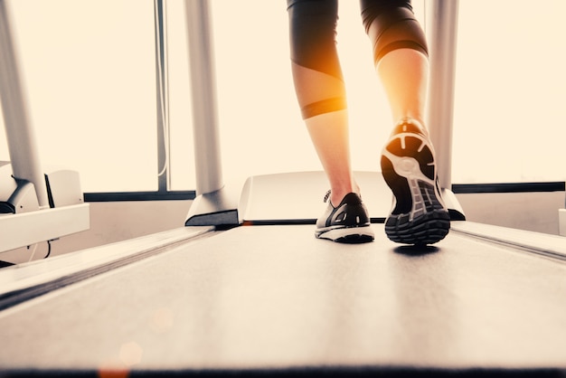 Onderlichaam bij benendeel van Geschiktheidsmeisje die bij het runnen van machine of tredmolen in fitness gymnastiek lopen