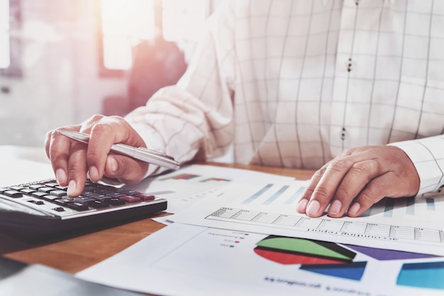 Onderneemster die aan bureau in bureau werkt en calculator en laptop met behulp van