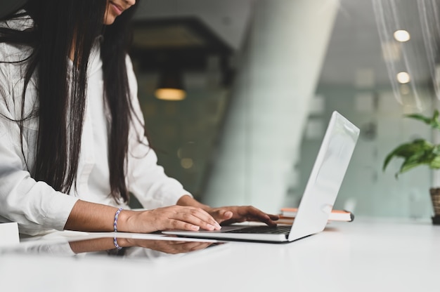 Onderneemster die aan laptop computer op witte lijst werkt