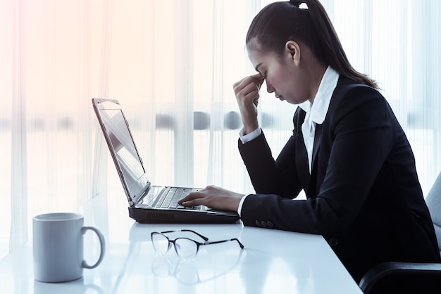 Onderneemster die computer in het bureau met behulp van. Stress op kantoor