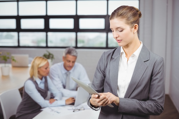 Onderneemster die digitale tablet gebruiken terwijl collega op achtergrond