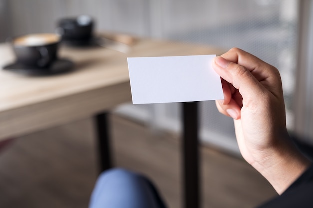 Onderneemster die een leeg adreskaartje houdt terwijl het zitten in bureau