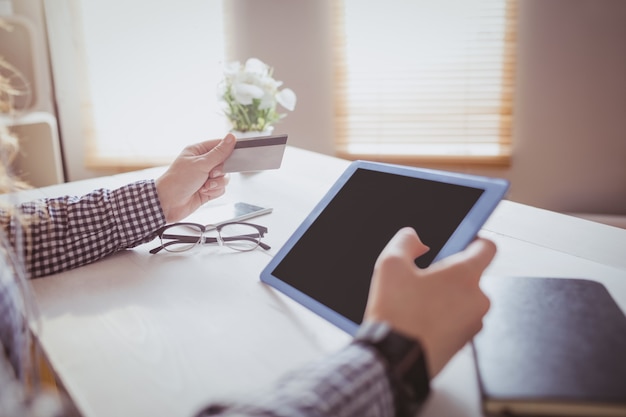 Onderneemster die haar creditcard gebruiken om online bij haar bureau in bureau te kopen