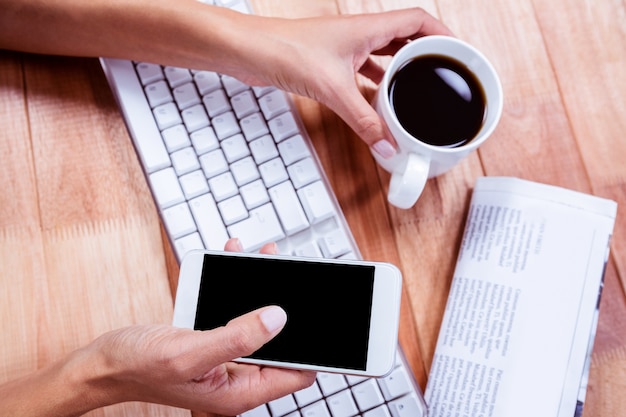 Onderneemster die haar smartphone op bureau gebruikt