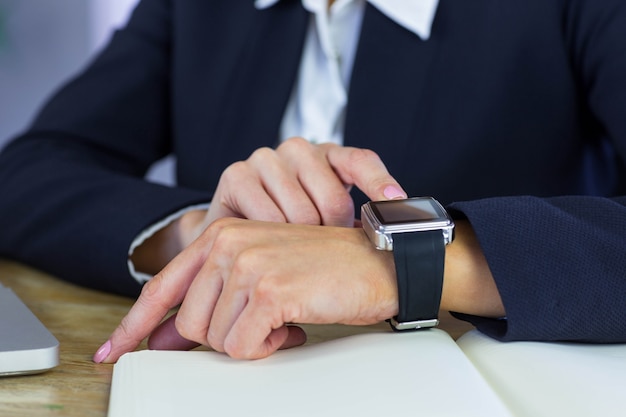 Onderneemster die haar smartwatch met behulp van bij bureau