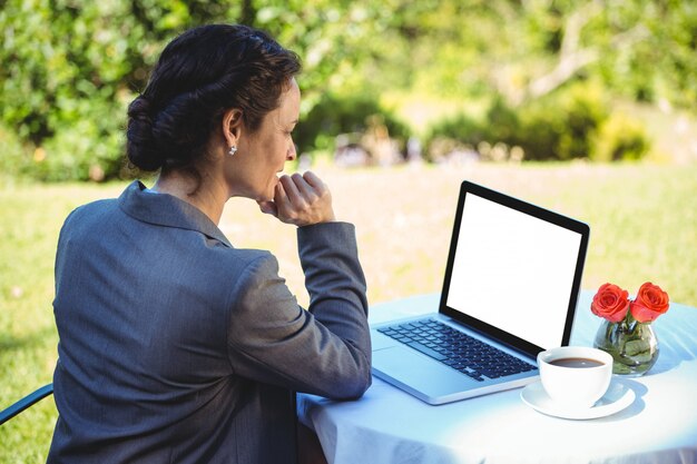 Onderneemster die koffie heeft die haar laptop met behulp van