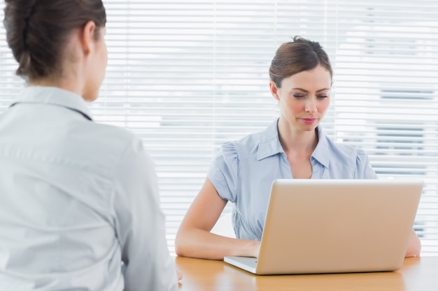 Onderneemster die laptop tijdens een gesprek bekijkt