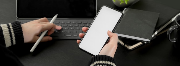 Onderneemster die met digitale tablet werkt terwijl het kijken van informatie over smartphone