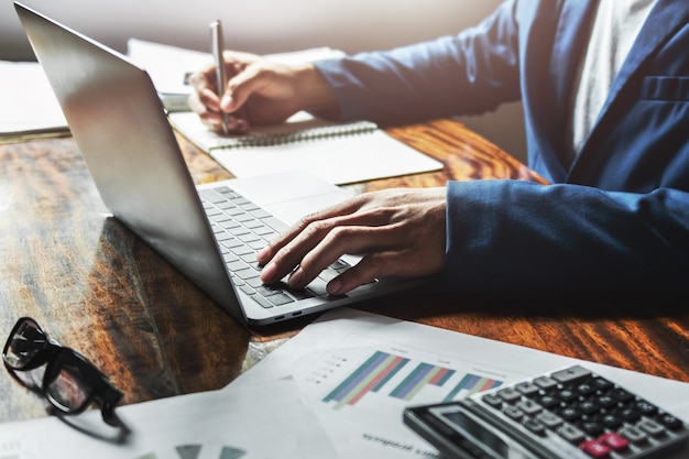 Onderneemster die met het gebruiken van laptop aan bureau in bureau werkt.