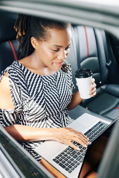 Onderneemster die met laptop in auto werkt