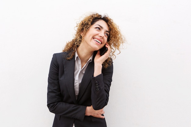 Onderneemster die op cellphone door witte muur spreekt