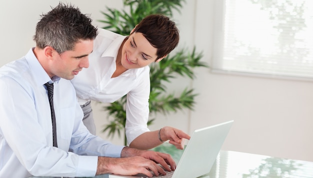 Onderneemster die op iets aan haar collega op een notebo richt