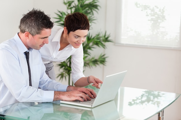 Onderneemster die op iets aan haar collega op laptop richt