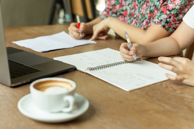 Onderneemster die project bespreken met en laptop van de koffiekop op lijst.