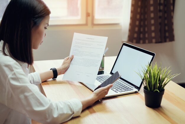 Onderneemster in bureau en gebruikscomputer om financiële boekhouding uit te voeren.