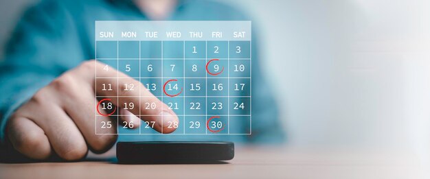 Foto ondernemer die aan zijn smartphone raakt met een kalender en een rode cirkel voor het boeken van herinneringen, afspraken, vergaderingen en het plannen van schemaconcepten