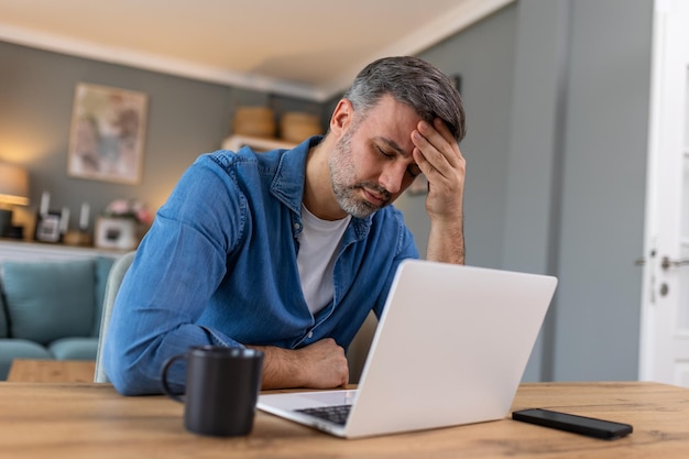 Ondernemer die op kantoor werkt met hoofdpijn van het bureau en de hele dag zit en werkt met een laptop of notebook die hoofdpijn heeft zieke werknemer die overwerkt