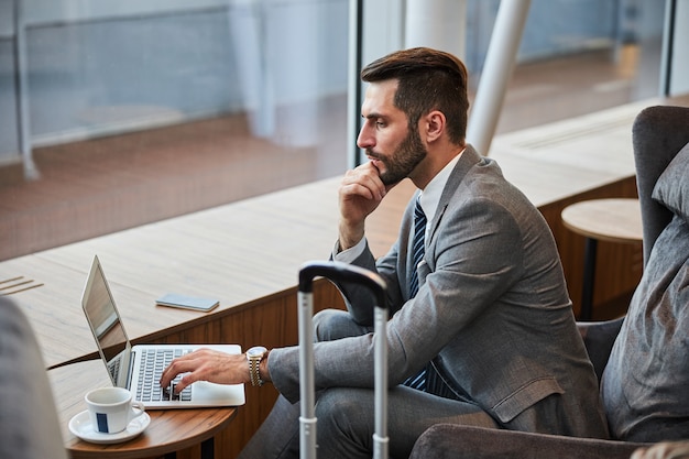 Ondernemer die op zijn laptop bij het raam werkt