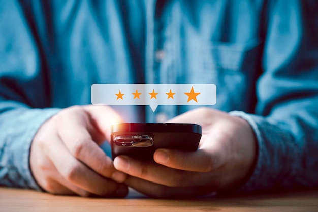 Foto ondernemer gebruikt smartphone om gouden vijf sterren te geven aan de klant de beste tevredenheid evaluatie enquête na gebruik product en dienst concept