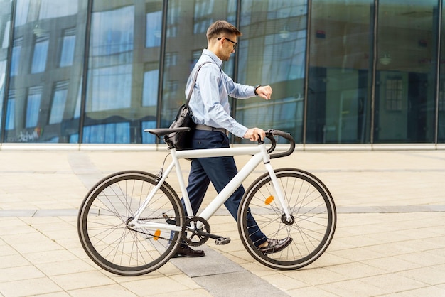 Ondernemer kijkt naar de tijd terwijl hij naast zijn fiets loopt in een stedelijke omgeving