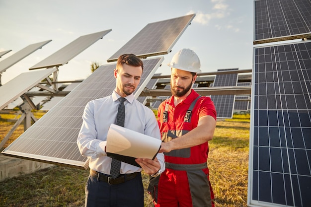 Ondernemer leest papieren met aannemer in zonne-energiecentrale