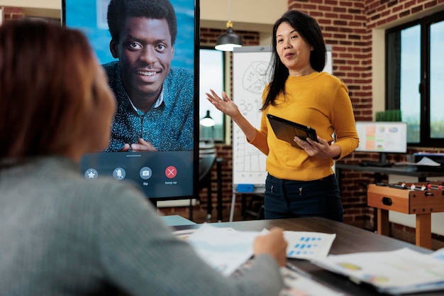 Ondernemer legt managementstrategie uit met externe manager tijdens online videocall-vergaderingsconferentie in startup-kantoor. Commercieel team dat bij bedrijfsproject werkt. Teleconferentiegesprek op monitor