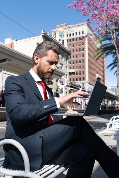 Ondernemer of manager. wendbaar bedrijf. professionele uitvoerende houd computer buiten. baas met moderne draadloze laptop. bebaarde zakenman die online werkt. zakelijk succes. programmeur man gebruik pc.