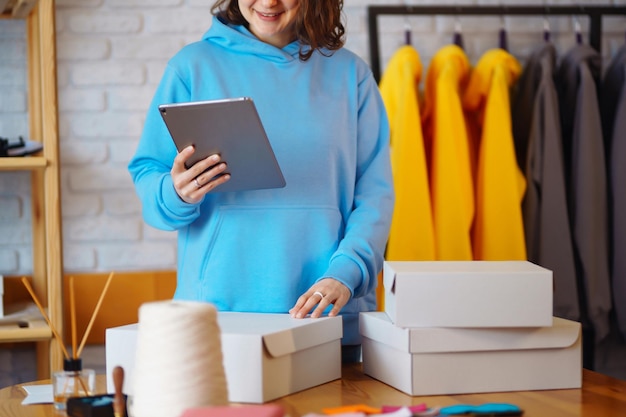 Ondernemer verkoper van kleine bedrijven die tablet gebruikt om bestellingen van e-commerce kledingwinkels te controleren