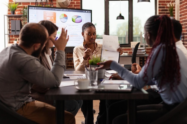 Ondernemers die werken bij marketingpartnerschap bespreken bedrijfsstatistieken die bedrijfspresentatie plannen in startbureau. Diverse businessteam brainstormen projectideeën