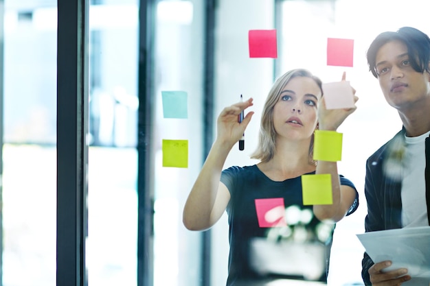 Ondernemers in brainstorm denk- en planningssessie in een modern kantoor Creatief team dat ideeën en strategie deelt voor samenwerking op de werkplek Mensen uit het bedrijfsleven aan het werk met plaknotities