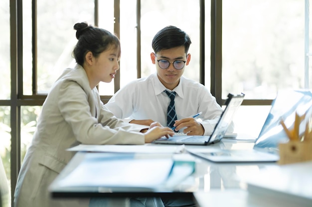 Ondernemers werken door te discussiëren en analyseren hun project met behulp van laptop en rekenmachine