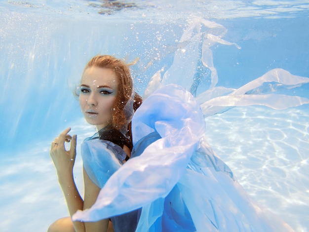 Onderwater mode portret van mooie jonge vrouw in blauwe jurk