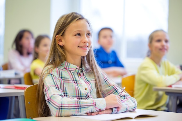 onderwijs, basisschool, leer- en mensenconcept - groep schoolkinderen met notitieboekjes die in de klas zitten