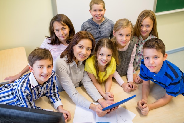 onderwijs, basisschool, leren, technologie en mensen concept - groep schoolkinderen en leraar met tablet pc-computer in de klas