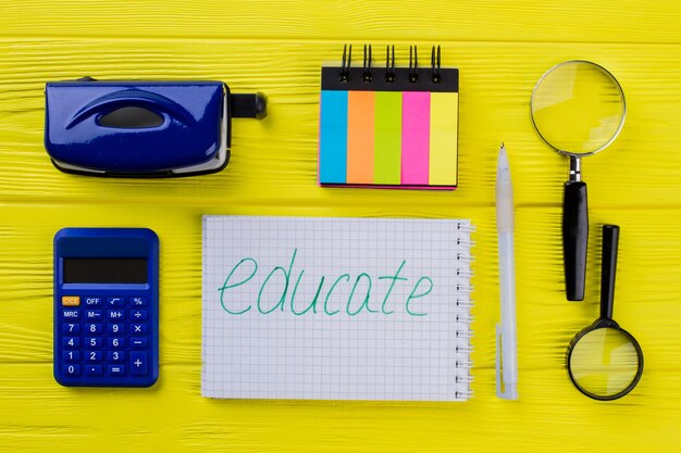 Onderwijs briefpapier items villen. Bovenaanzicht Kladblok met rekenmachine en vergrootglas op geel hout.