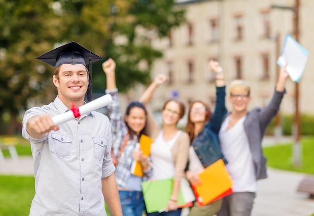 Onderwijs, campus en tienerconcept - glimlachende tiener in hoekpet met diploma en klasgenoten op de rug