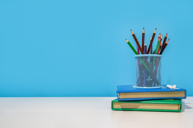 Onderwijs concept. potloden in potloodhouder en boeken op witte tafel