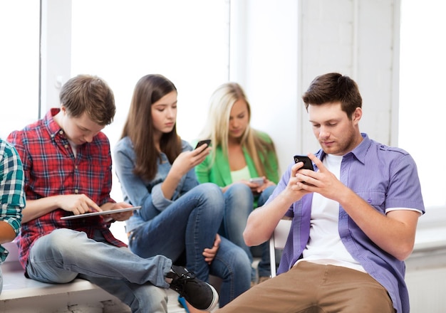 onderwijs- en internetconcept - studenten op zoek naar telefoons en tablet-pc